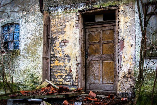 Ein zerfallendes Haus mit defektem Fenster und einer alten Tür